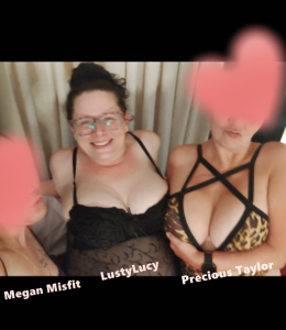 Cam models Megan Misfit, LustyLucy and Precious Taylor posing for the camera. Megan and Taylor's faces are mostly obscured by hearts, but you can see Taylor's huge breasts in her animal print lingerie as well as Lucy's in her black teddy while she gives a huge toothy smile.