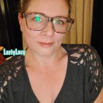 Cam model and content creator LustyLucy in glasses with her hair tied back and a slight smile on her face.